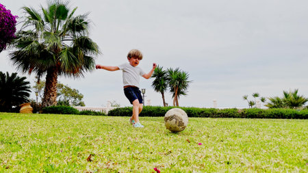 Young player boy chases soccer ball to score goal in a gateの写真素材