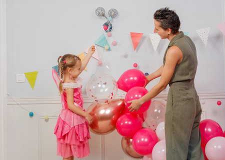 Mom with little girl decorate room for children birthday partyの写真素材