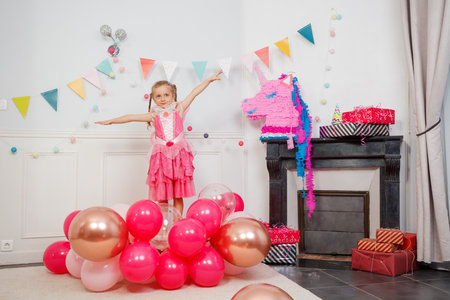 Smiling kid stand in fairy dress at colorful party with balloonsの写真素材