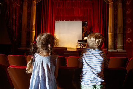 Kids eagerly looking at a stage with piano, waiting for showの写真素材