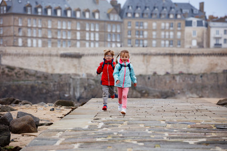 Kids with backpacks, smiling and run by the coast in Saint-Maloの写真素材
