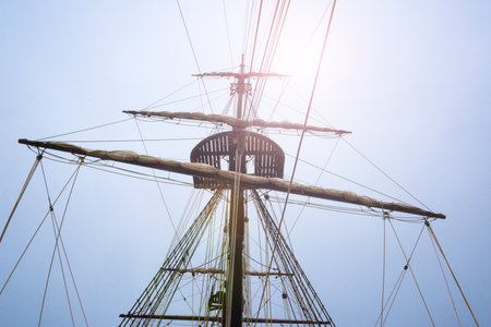 Mast and rigging of the ship silhouetted by bright sunlit skyの写真素材