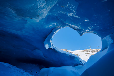 Blue ice cave and mountains through heart-shape entranceの写真素材