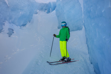 Young skier poses with skis in frozen terrainの写真素材