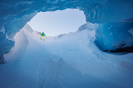 Exciting skiing through a blue ice tunnel with vibrant outfitの写真素材