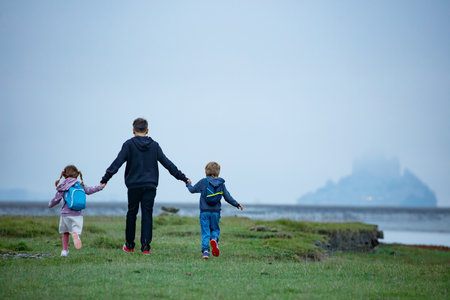 Little adventurers stroll across field, aiming for misty island