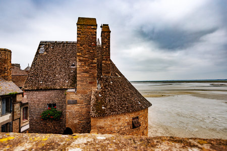 Old stone castle wall of Mont Saint Michel beside sandy shoreの写真素材