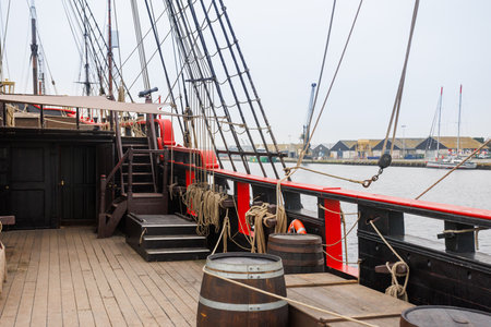 Historic sailing ship docked with barrels and ropes on the deckの写真素材