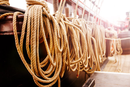 Sunlit ropes are neatly arranged on the deck of a sailing shipの写真素材