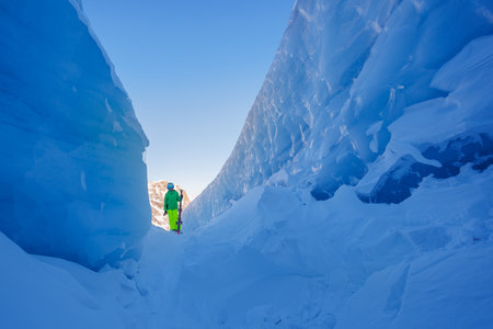 A vibrant skier boy stand on snowy path flanked by icy cliffsの写真素材