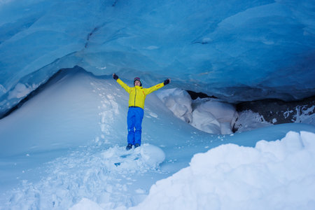 Skier man exploring a stunning blue ice cave in bright attireの写真素材