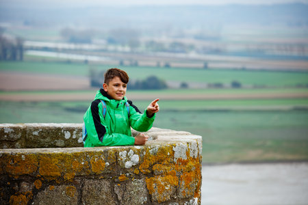 A boy pointing from stone lookout tower of Mont Saint Michelの写真素材
