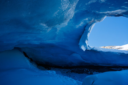 Blue ice cave with bright light seeping through ceiling openingの写真素材