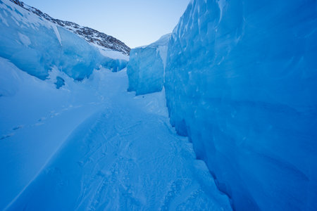 Stunning blue ice canyon with rugged, snowy walls in mountainsの写真素材
