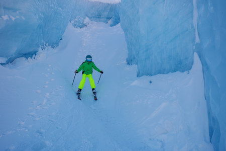 Skier in bright gear navigates icy glacier passage at mountainsの写真素材