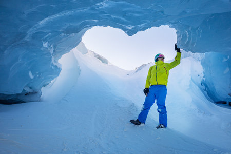 Skiing stand under a breathtaking blue ice arch in the mountainsの写真素材