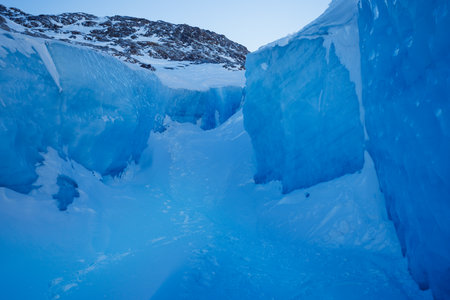 Majestic icy passage with deep blue frozen walls and mountainsの写真素材