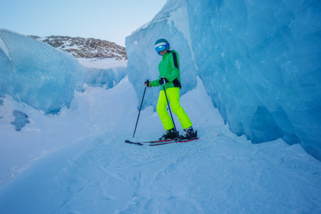 Through narrow glacier passage, boy in skiing gear slides downの写真素材