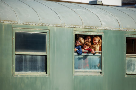 Two children wave from train window in warm late afternoon light