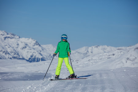 Skier in neon green jacket skis down a run under bright blue skyの写真素材