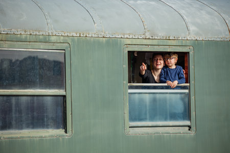 Mom with kid lean out green carriage window smiling at fieldsの写真素材