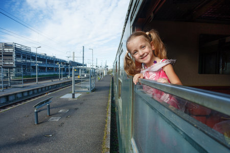Girl peers from train window in wonder at countryside sceneryの写真素材