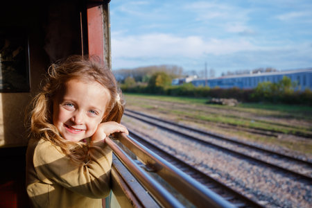 Smiling girl leans from carriage window at passing landscape