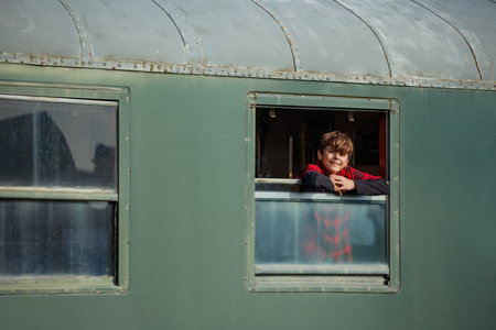 Curious teenager boy look out from a vintage trains window.の写真素材