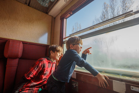 Brothers point in train window at scenery rushing by outsideの写真素材