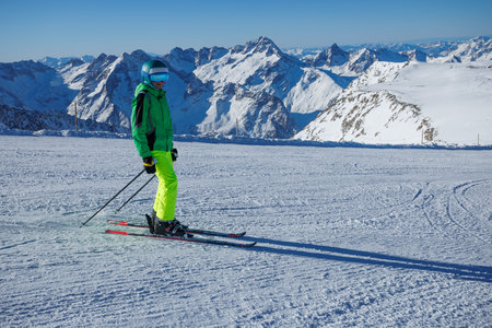 Adventurous skier in vibrant outfit tackles icy mountain slopesの写真素材