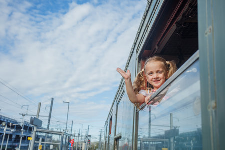 Girl leans from open train window wave joyfully at people belowの写真素材
