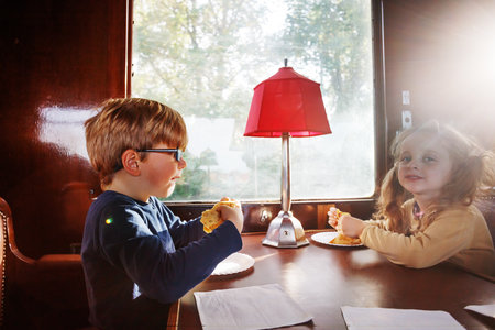 Brother and sister eat pancakes at a restaurant carriage tableの写真素材