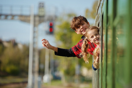 Children peer excitedly from train window at signals and railsの写真素材