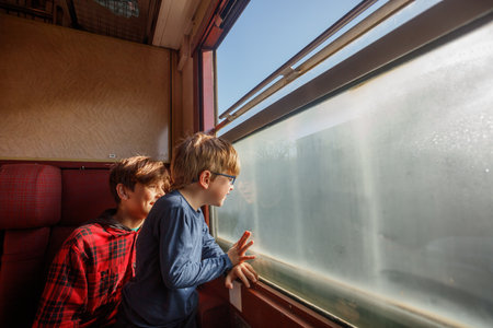 Boys lean on window sill pointing excitedly at passing fieldsの写真素材