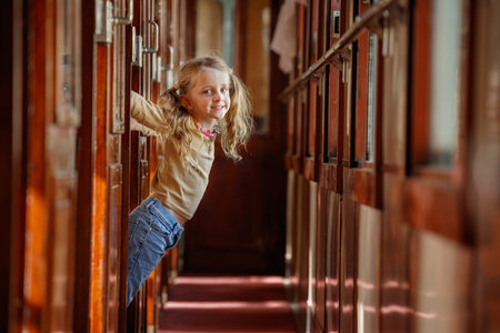 Little girl swings playfully from cabin doorway inside trainの写真素材