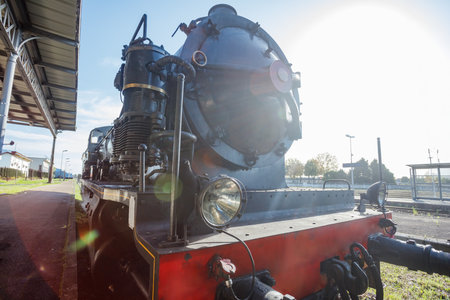 Steam locomotive stands at platform in sunlight under blue skyの写真素材