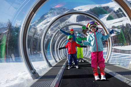 Skiers kids and adults ascending through a glass-enclosed liftの写真素材