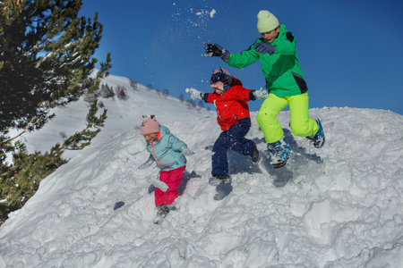 Joyful snow day with kids and adult jumping down energeticallyの写真素材