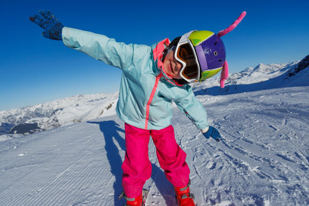 Child skiing in bright gear, posing happily on snowy slopesの写真素材