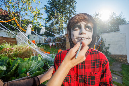 Artist paints black contours on teen skull face design outdoorsの写真素材