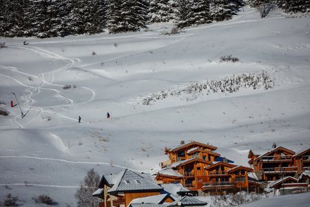 Cluster of wooden chalets dot snowy valley floor beneath peaks