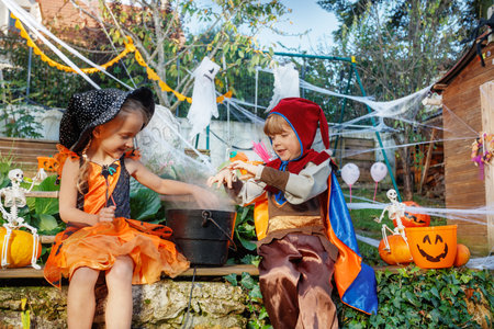 Fairy and pirate siblings share candies from a spooky cauldronの写真素材