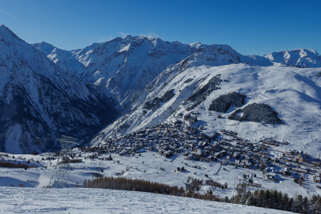 Snowy mountain village resort under clear blue skies in winterの写真素材