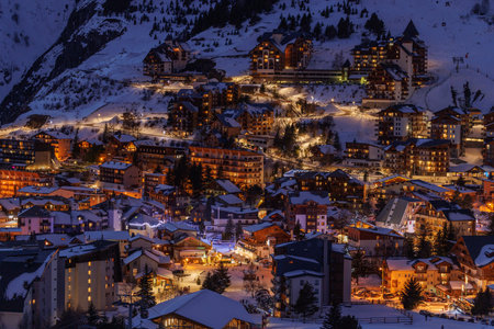 Snowy mountain resort village shines with lights under night sky