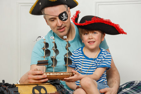 Pirate playtime: father with son play in ship model and chestの写真素材