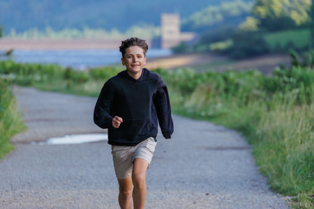 Boy in black hoodie run on scenic path along Howden reservoir
