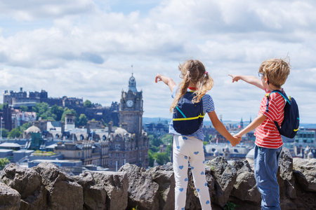 Children tourists enjoy scenic view over the city, holding handsの写真素材