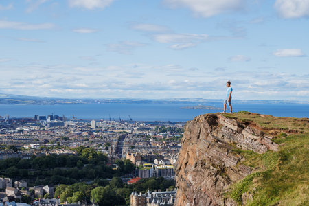 Man stand on top of Arthurs Seat, Edinburg overlook city and seaの写真素材