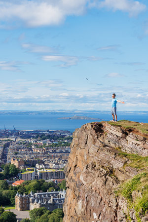 Man on a cliff enjoys Scottish highlands breathtaking panoramaの写真素材