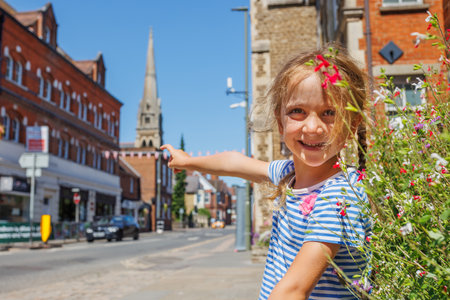 Girl in striped shirt smiles, point on sunny street, Farnham, UKの写真素材
